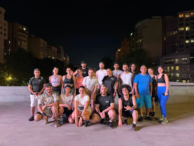 A large group posing on a floodlit plaza after a night run