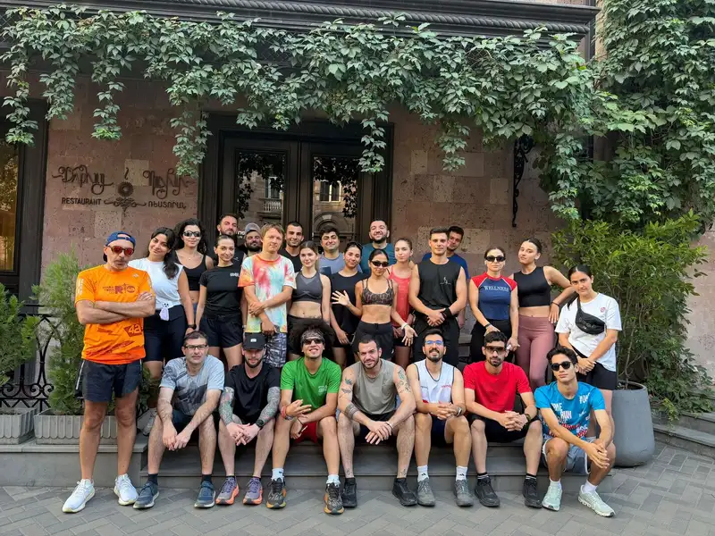 Runners sitting along the wall of an ivy-covered building after a morning run
