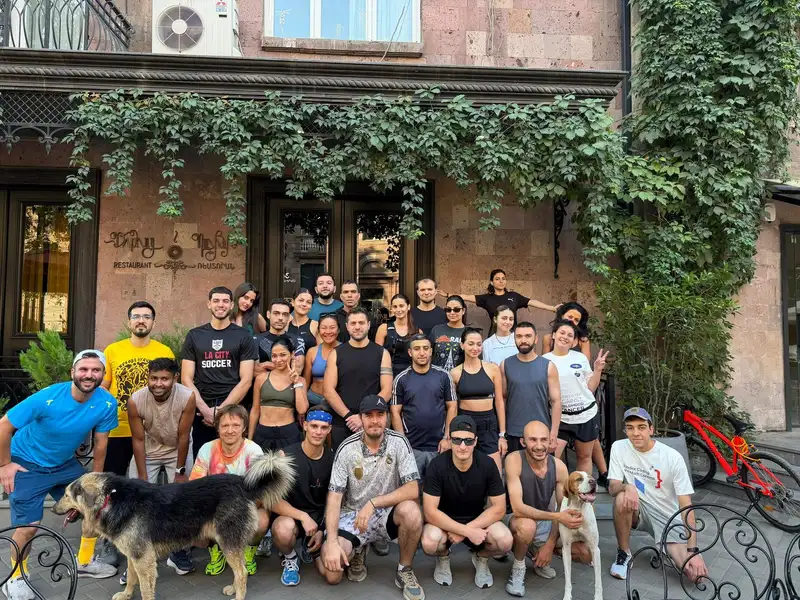 A big weekend group, with two dogs, outside a stone building
