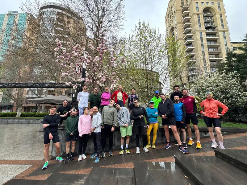 A large group posing beside flowering magnolia trees in a city square