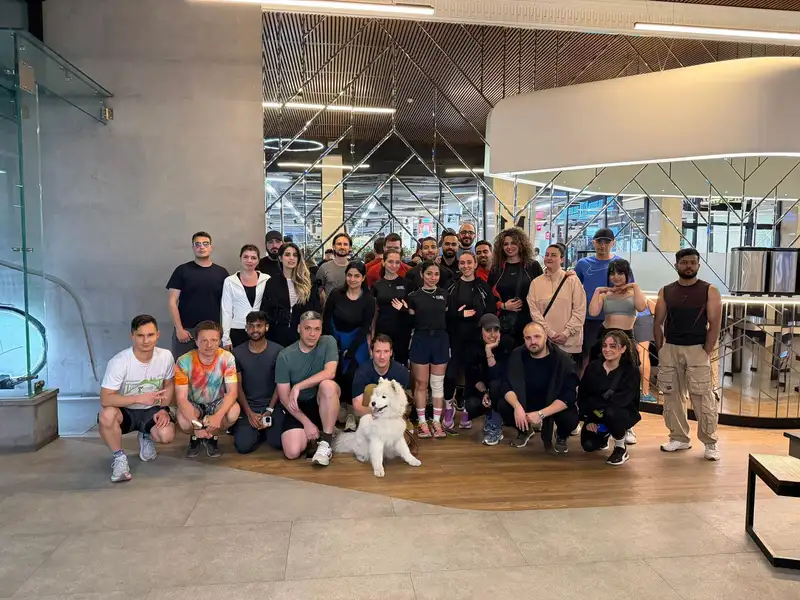 The club filling a bright mall atrium after a run, with a white dog in front