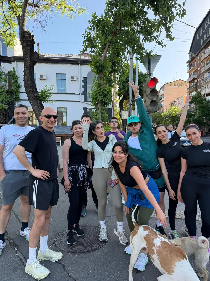 A small group on a street, one person leaping into the air, with a dog