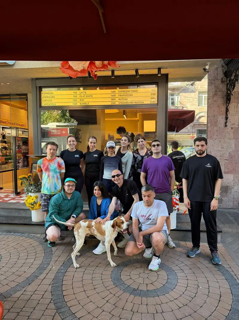 The group posing outside a coffee kiosk, a dog lying in front