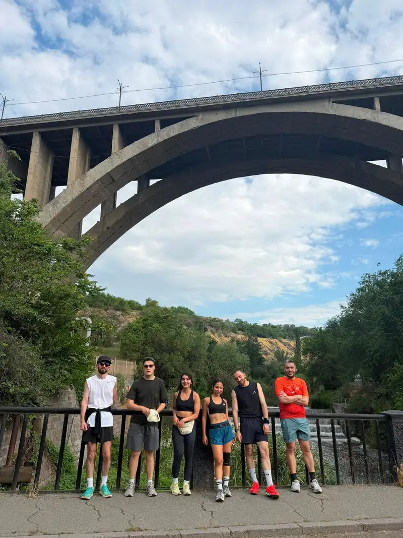 A group standing along a railing beneath a tall bridge arch