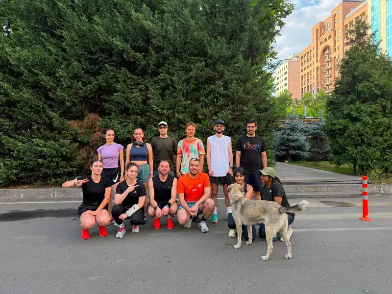 A group photo on a quiet street lined with trees, a dog in front