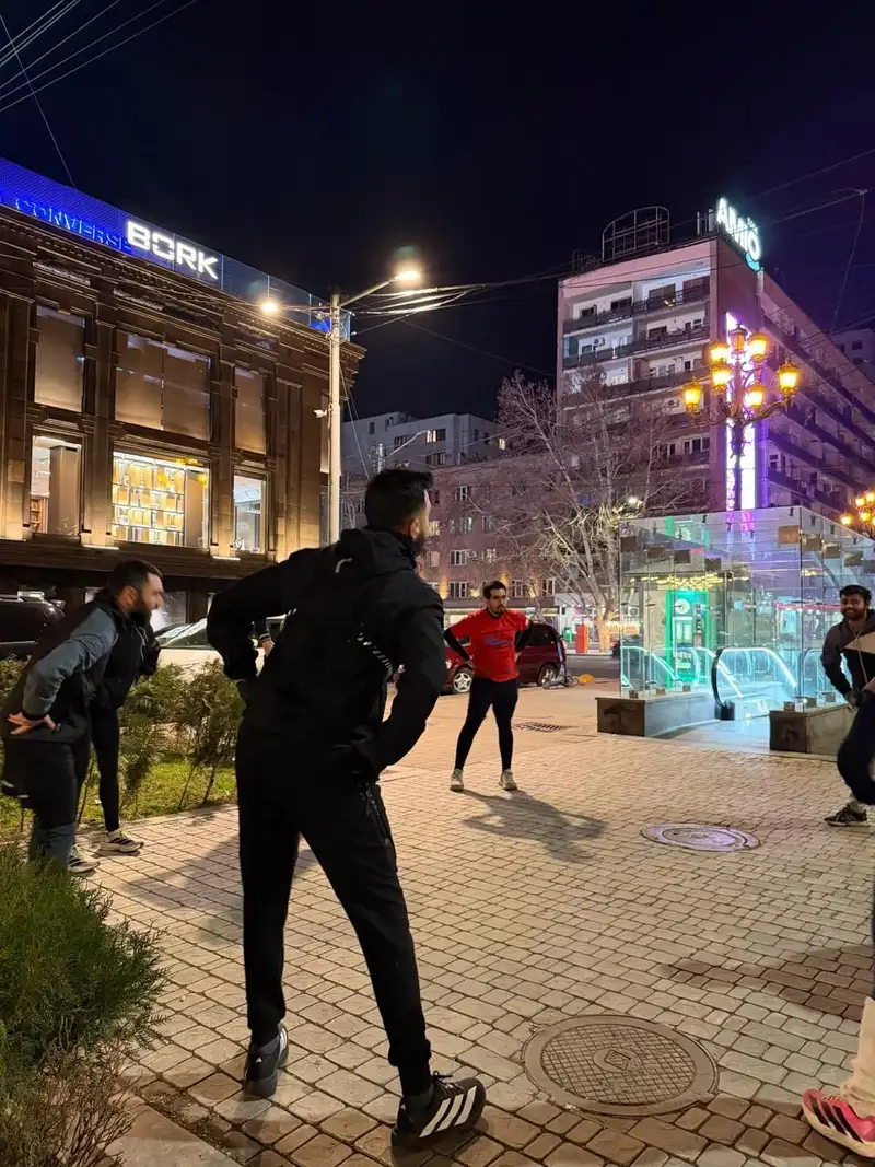 A runner stretching in a lit city square at night