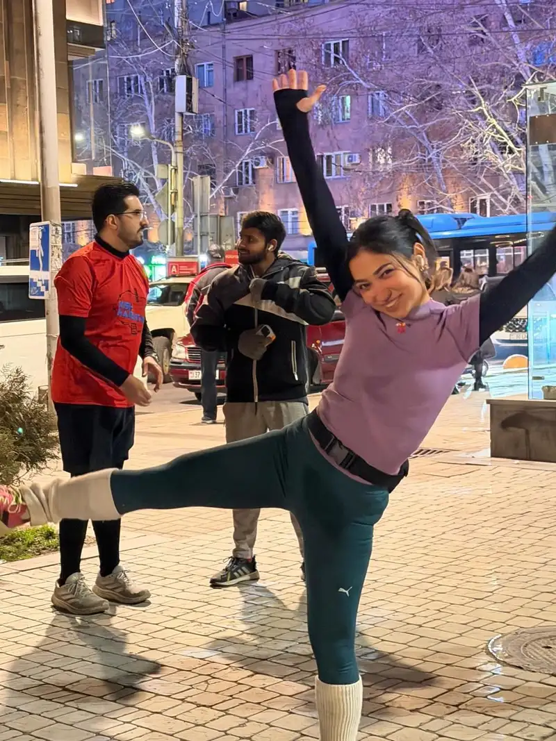 A runner balancing on one leg on a city street at night