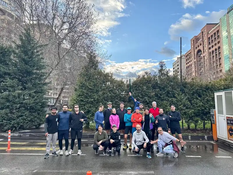 A big group on a wet street among evergreen trees