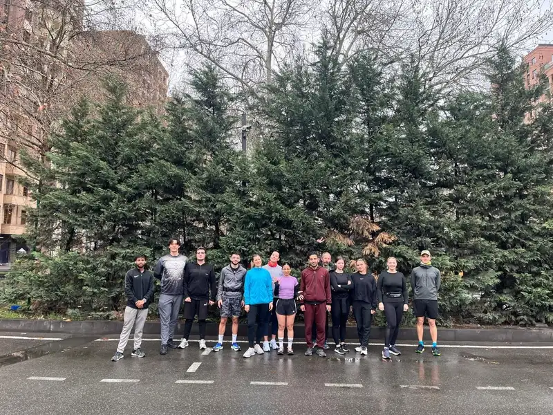 A long line of runners posing across a street on a grey day