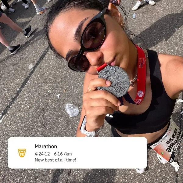 Shaghig holding up a marathon finisher medal at the end of a race