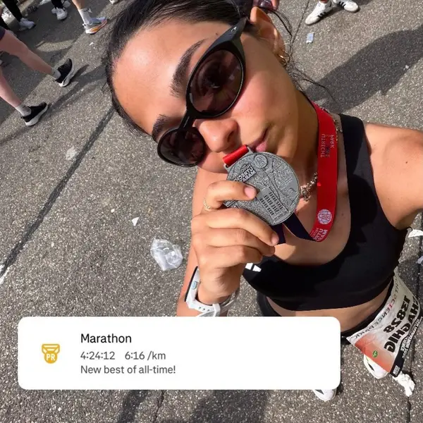Shaghig holding up a marathon finisher medal at the end of a race